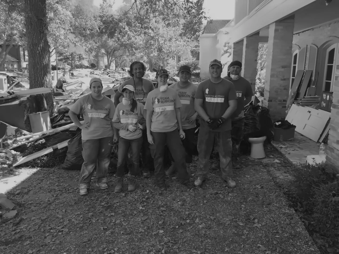 Courtney with a Team Rubicon crew in front of a flood-damaged house